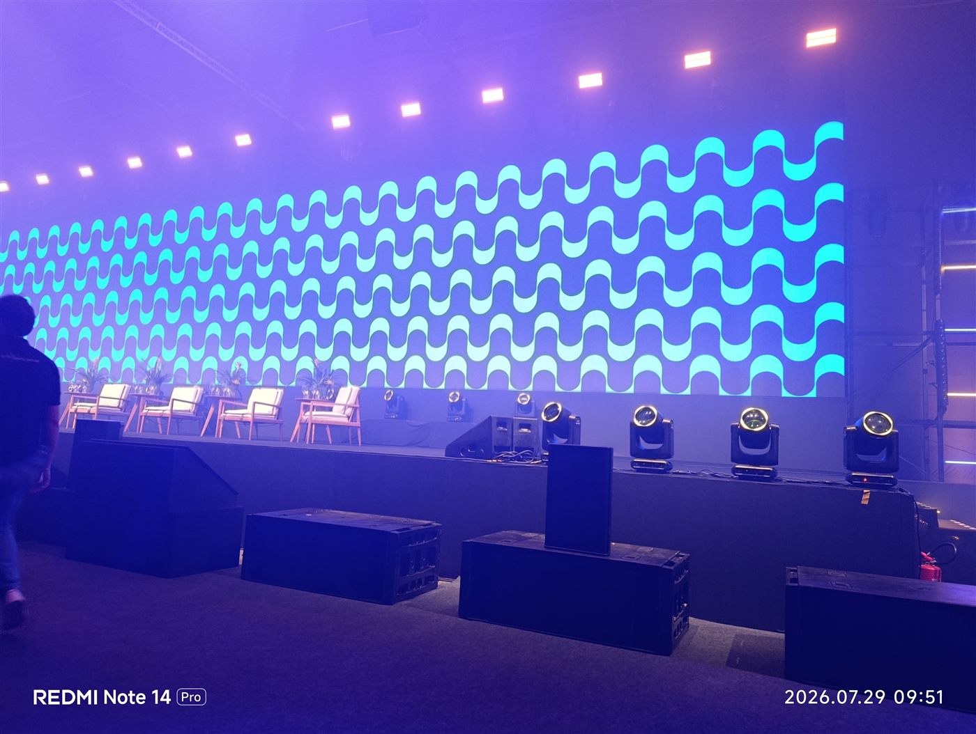 Palco corporativo com painel de LED ao fundo e movings no piso